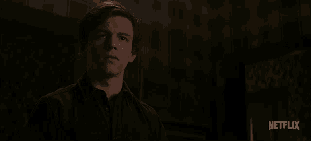 a man is sitting in a dark room with a netflix logo behind him