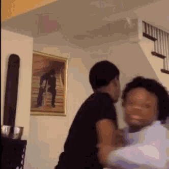 a man and a woman are fighting in a living room with stairs in the background .