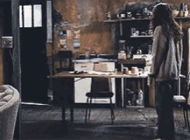 a woman is standing in a dark room in front of a table
