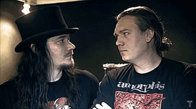 two men are looking at each other and one has a shirt that says amorphis on it