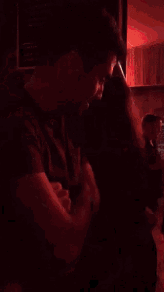 a group of people are dancing in a dark room with an exit sign above them