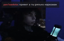 a man is sitting in a dark room holding a microphone and looking at his phone