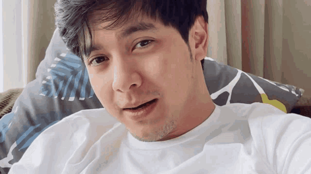 a man in a white shirt is laying on a bed