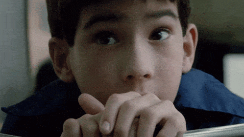 a close up of a child 's face with his hands on his face