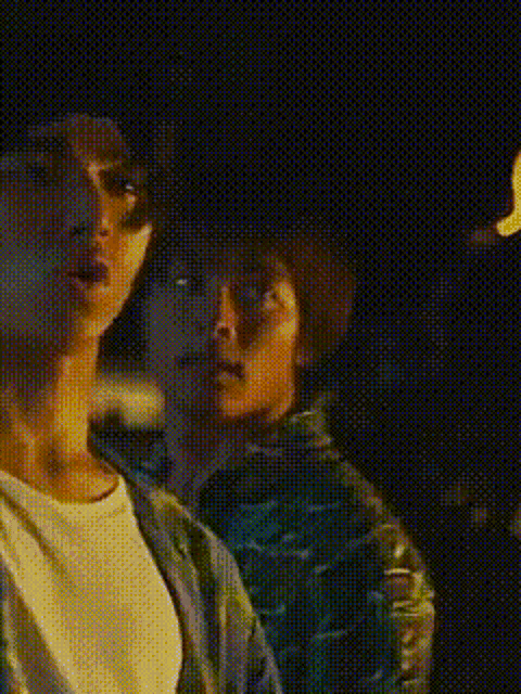 a man and a woman are standing next to each other in the dark looking at something .