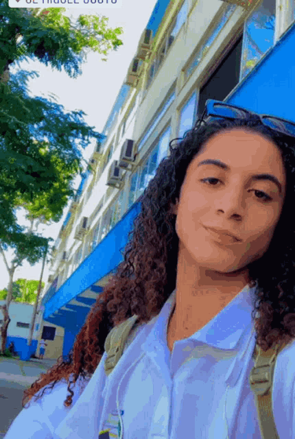 a woman taking a selfie in front of a building that says ' uc thruell ' on it
