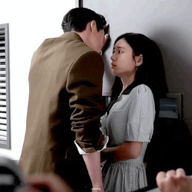 a man and a woman are kissing against a wall