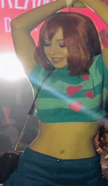 a woman in a crop top is dancing in front of a sign that has the letter b on it
