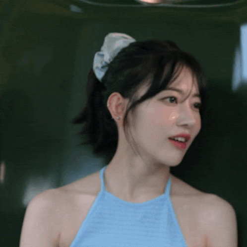 a woman wearing a blue halter top has a bow in her hair