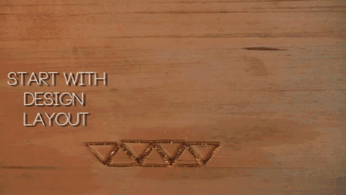 a person with a ring on their finger is drawing triangles on a wooden table