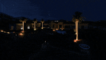 a white car is parked in front of a house with palm trees