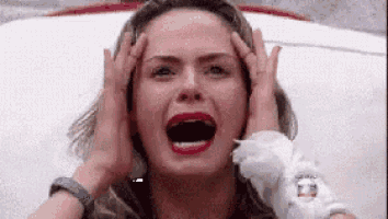 a woman is screaming and holding her head with her hands .