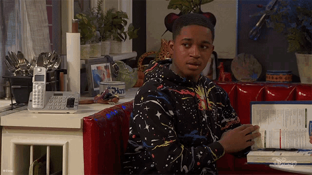 a young man sitting in a diner booth looking at a menu with disney written on it