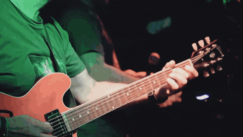 a man in a green shirt plays a gibson guitar