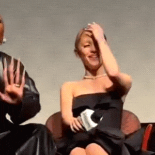 a woman in a black dress is sitting on a chair with her hand on her head