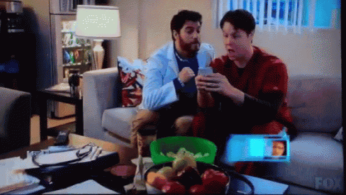 two men are sitting on a couch in front of a fox television screen
