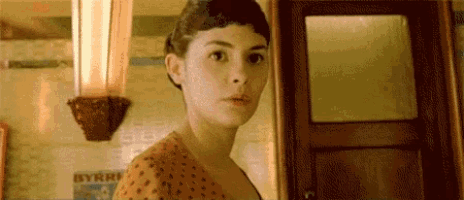 a woman in a polka dot dress is standing in front of a door looking at the camera .