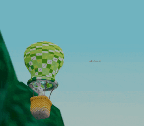 a green and white hot air balloon is flying over a hill