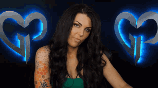 a woman with a tattoo on her arm is standing in front of a heart with the letter g on it