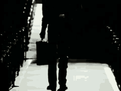 a man is walking down a dark hallway with a briefcase .