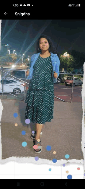 a woman in a green polka dot dress is standing in front of a parking lot