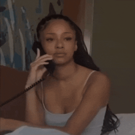 a woman is sitting in bed talking on a telephone .