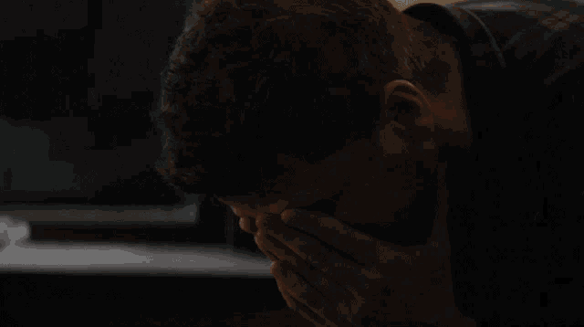 a man covering his mouth with his hands while looking down