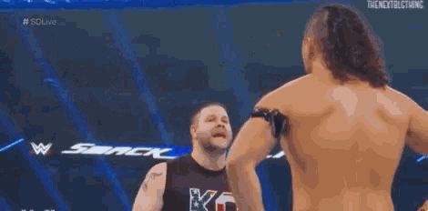 two men are wrestling in a wrestling ring with a referee watching .