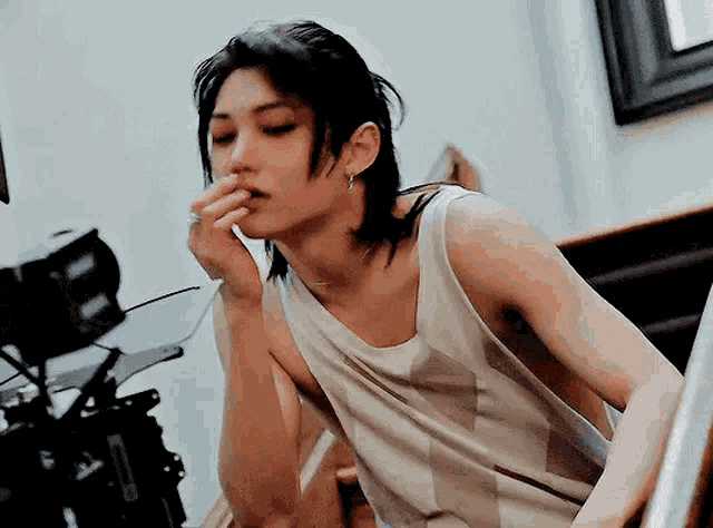 a young man with long hair is smoking a cigarette while sitting on stairs .