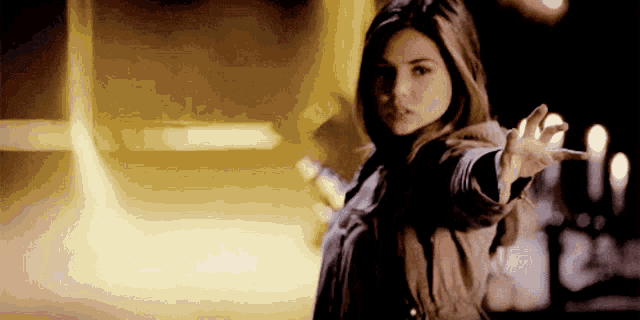 a woman is standing in front of a blurry background and reaching out her hand
