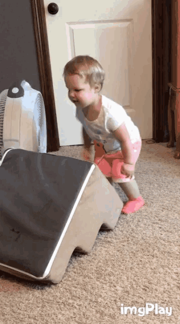 a little girl is standing next to a box that says ' imgplay ' on it