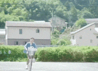 a man is riding a bicycle down a road in front of a row of houses .