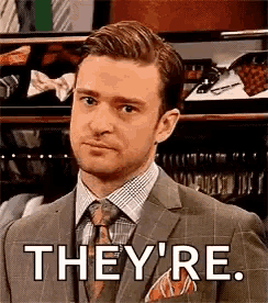 a man in a suit and tie is standing in front of a closet and says `` they 're '' .