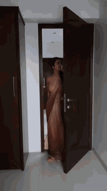 a woman in a saree stands in a doorway