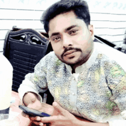 a man with a beard is holding a cell phone in his right hand