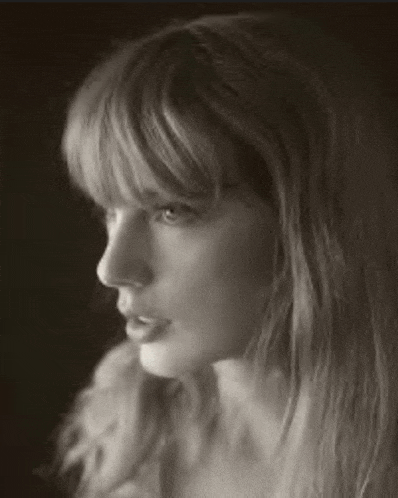 a black and white photo of a woman with long hair and bangs looking at the camera .