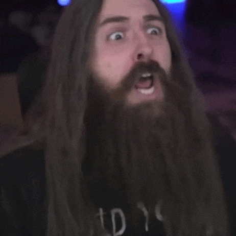 a man with long hair and a beard is making a funny face with his mouth open .