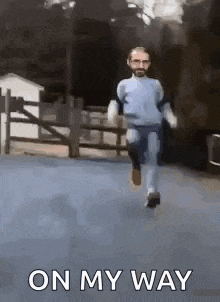 a man with a beard is running down a street with the words `` on my way '' behind him .