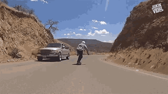 a man riding a skateboard down a road next to a truck with jukin video written on it