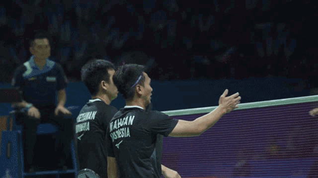 a group of men are playing badminton and one of them has the name mahsan indonesia on the back of his shirt
