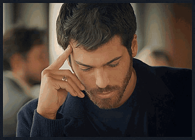 a man with a ring on his finger is holding his head