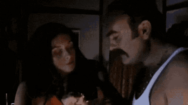 a man is drinking from a bottle while a woman looks on .