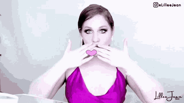 a woman in a purple dress is blowing a kiss to the camera .