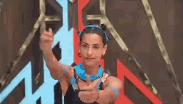 a woman is giving a thumbs up sign while standing in front of a wall .