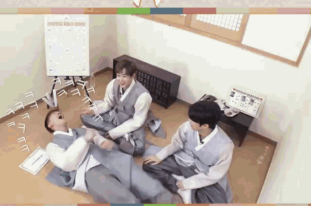 a group of young men are sitting on the floor laughing and playing with each other .