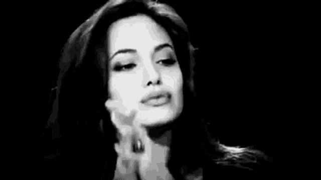 a black and white photo of a woman talking on a cell phone in a dark room .