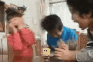 a group of people are sitting at a table talking to each other in a living room .