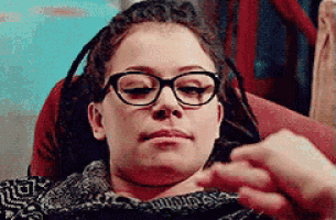 a woman wearing glasses is laying on a couch .