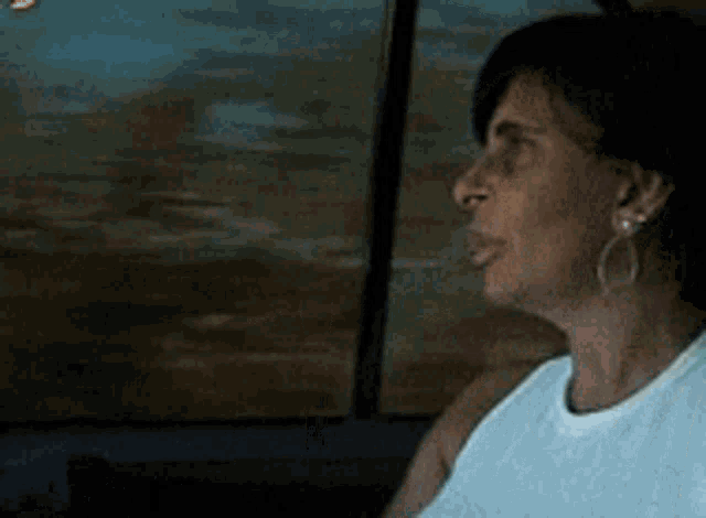 a woman is sitting in a car looking out the window at the beach .