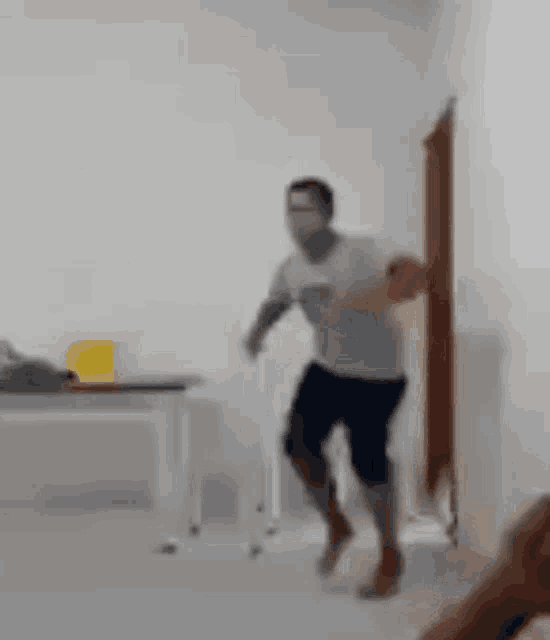 a man is jumping in the air in a room with a table and chairs .